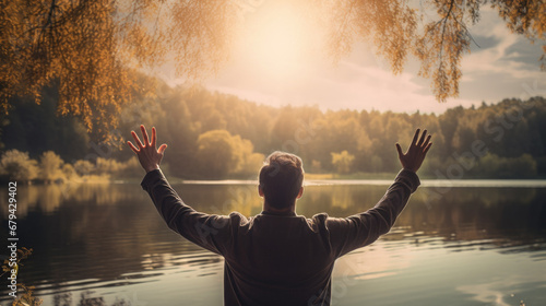 Fotografering believer with hands raised in prayer by a serene lakeside, showcasing their spir