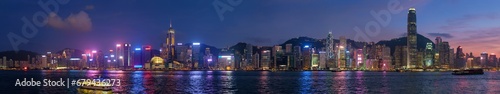 Panorama of Hong Kong skyline cityscape downtown skyscrapers over Victoria Harbour in the evening illuminated tourist boats and ferries . Hong Kong, China photo