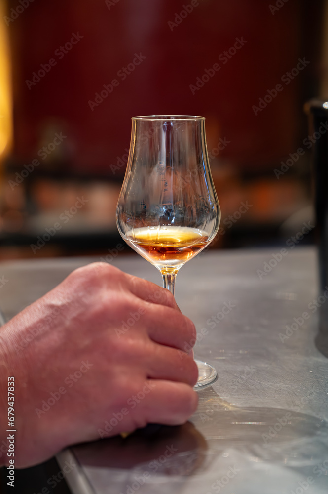 Obraz premium Tasting of cognac spirit aged in old French oak barrels in cellar in distillery in Cognac white wine region, Charente, Segonzac, Grand Champagne, France