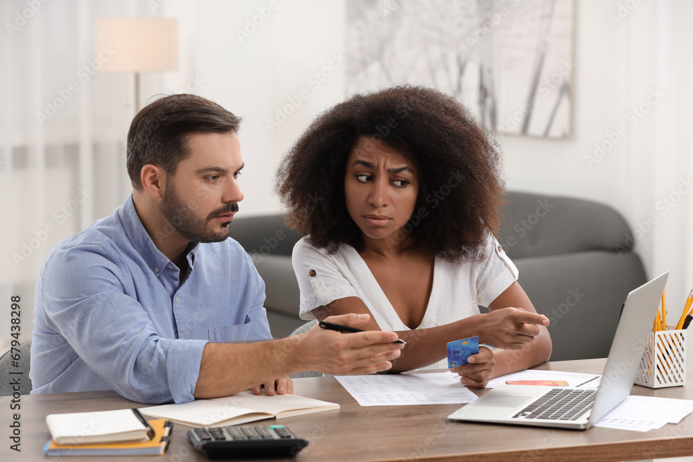 Confused couple with credit card using laptop for planning budget at home. Debt problem Confused couple with credit card using laptop for planning budget at home. Debt problem