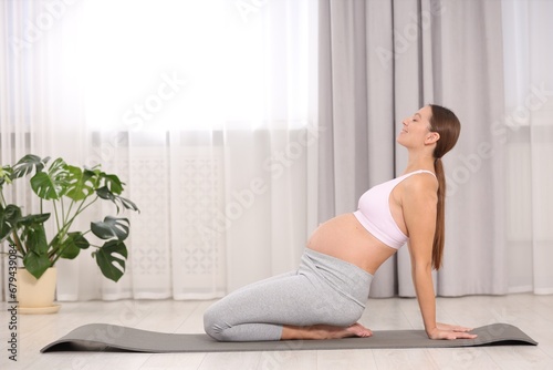 Pregnant woman doing exercises on yoga mat at home