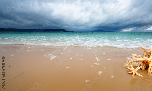 beach with crystal clear water and starfish with stormy sky