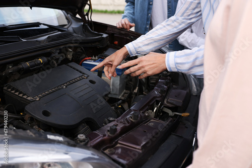 Driving school. Teacher explaining car engine to group outdoors, closeup