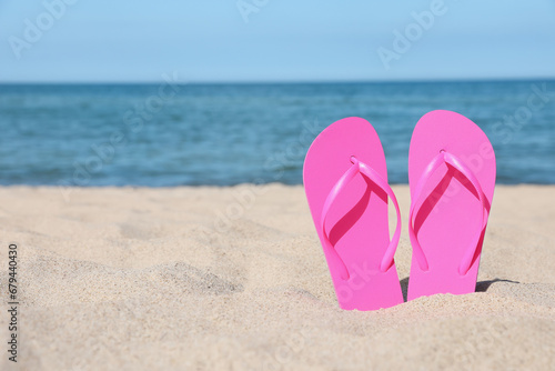 Stylish pink flip flops on beach sand, space for text