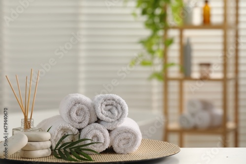 Spa composition. Towels, reed diffuser, stones and palm leaves on white table in bathroom, space for text
