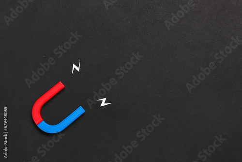 Plakat w ramie Horseshoe shaped magnet with paper lightnings on grunge black background