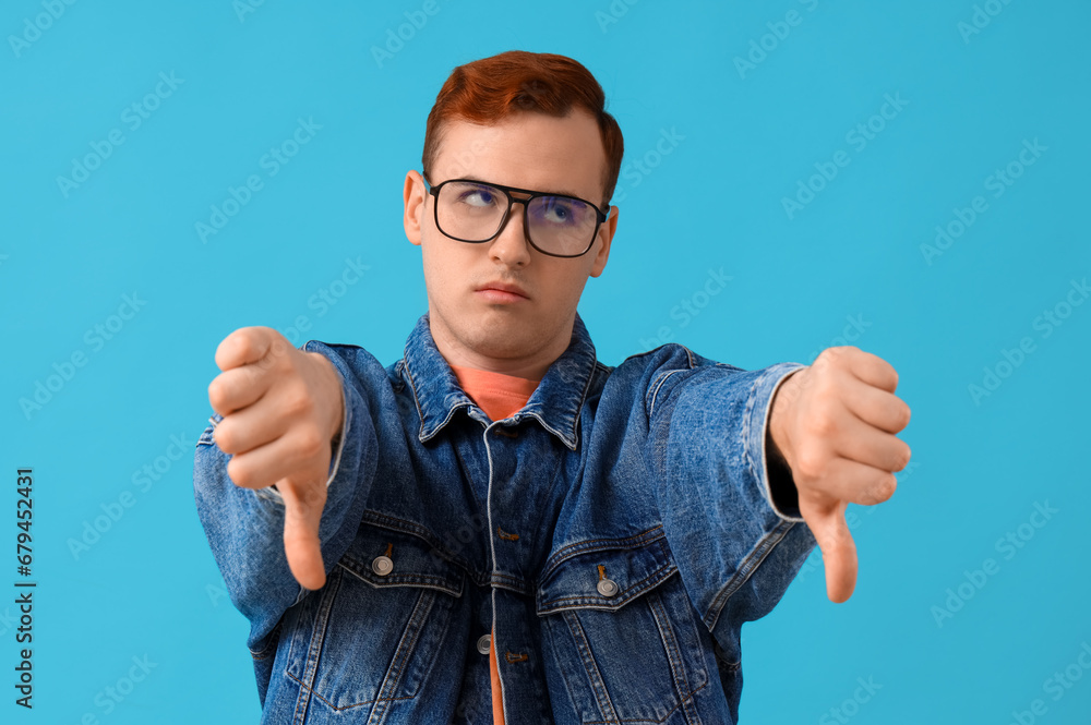 Young man showing dislike on blue background Young man showing dislike on blue background