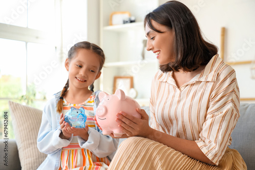 Little girl and her mother with piggy banks at home