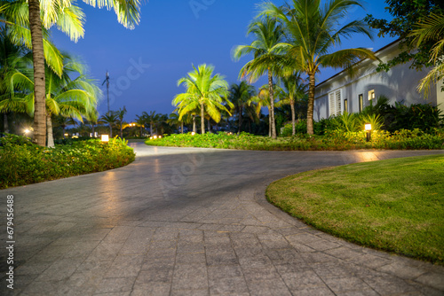 Road in resort park at night with palm trees on background. Soft focus
