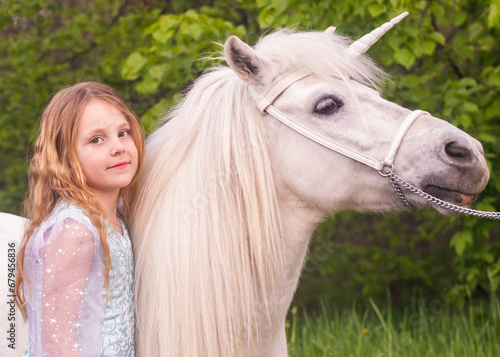 Portrait. A beautiful elegant girl with a magical fairy unicorn. A girl and a white pony. The child is a model.