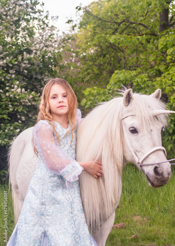 Portrait. A beautiful elegant girl with a magical fairy unicorn. A girl and a white pony. The child is a model.