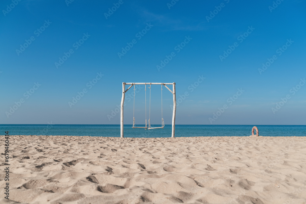 Empty swing on tropical beach with blue sky