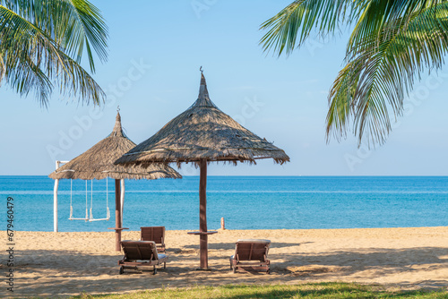 Tropical beach with palm tree and leaf umbrellas