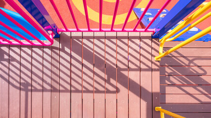 Sunlight and shadow on surface of different walkway level of modern outdoors playground equipment on rubber floor in playground area at kindergarten, view from above