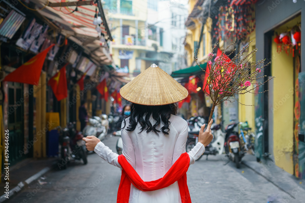 Φωτογραφία Vietnamese girl with traditional dress (ao dai) on Hanoi street with peach flowe