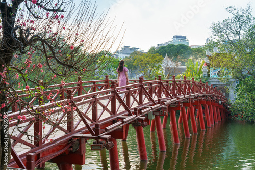 Red bridge The Huc in Hoan Kiem lake, Hanoi, with blooming peach flowers on foreground photo