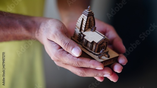 hands holding a wooden figure of kedarrnath dham photo