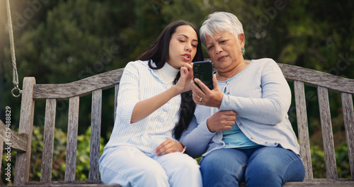 Phone, senior or mother with woman on bench in nature reading news on social media in retirement. Online gossip, mature parent or daughter for together in park or garden as a family with mobile app