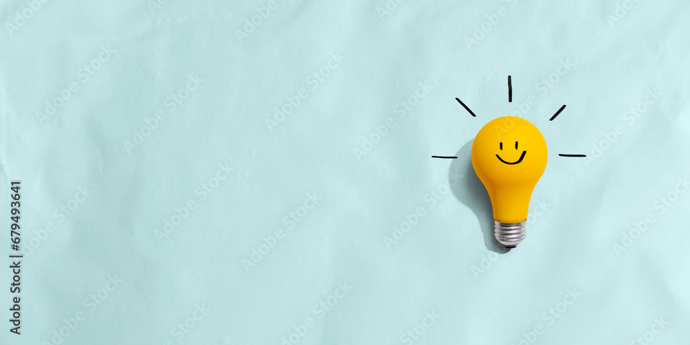 Yellow light bulb with happy face - flat lay - obrazy, fototapety, plakaty 