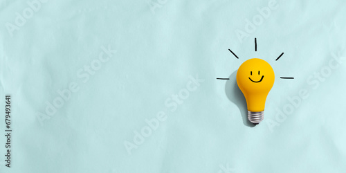 Yellow light bulb with happy face - flat lay