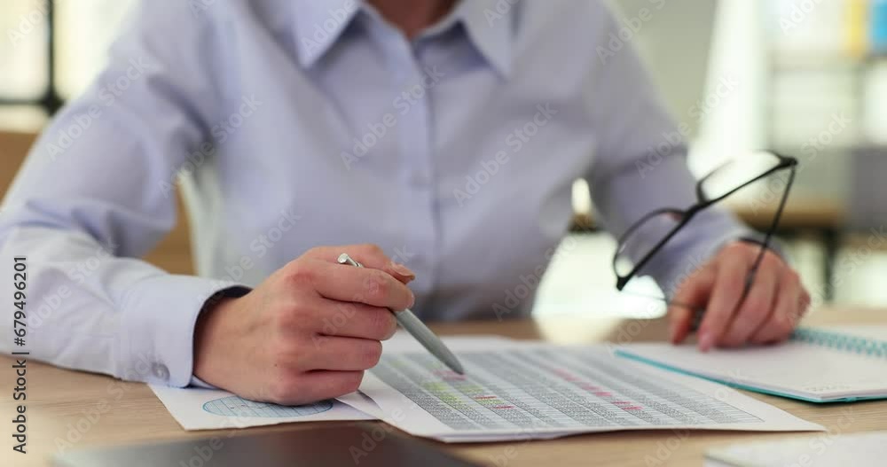 Woman hands holding financial report with pen and glasses Woman hands holding financial report with pen and glasses
