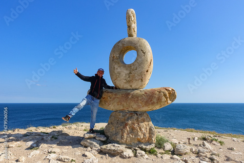 A man near the sculpture Thinker is the Heart of Tarkhankut. The Black Sea. Turquoise sea water. Rocks and grottoes of Cape Tarkhankut on the Crimean peninsula. photo