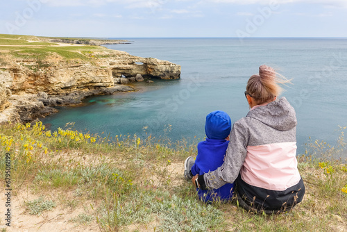 A girl with a child on Cape Tarkhankut. The rocky coast of the Dzhangul Reserve in the Crimea. Turquoise sea water. Rocks and grottoes of Cape Tarkhankut on the Crimean peninsula. photo