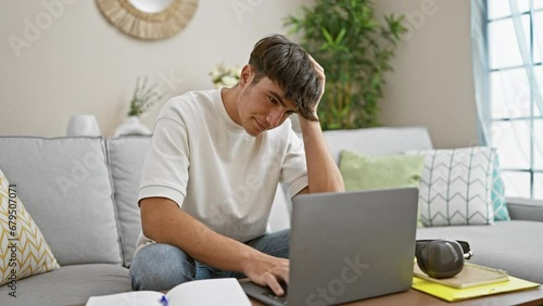 Stressed out young hispanic teenager sitting, studying on his laptop at home, face focused, struggling with online education on the living room sofa photo