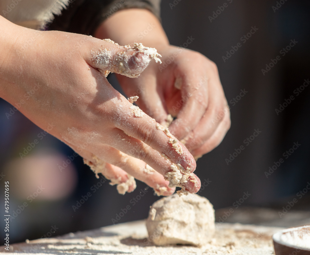 A woman kneads the dough with her hands