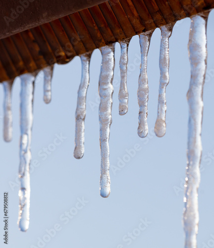 Icicles hang from the roof against the blue sky