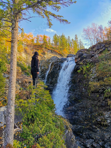 A girl on the background of a beautiful waterfall in the autumn mountains beyond the Arctic Circle in the north, in Khibiny, Murmansk region. Kola Peninsula photo