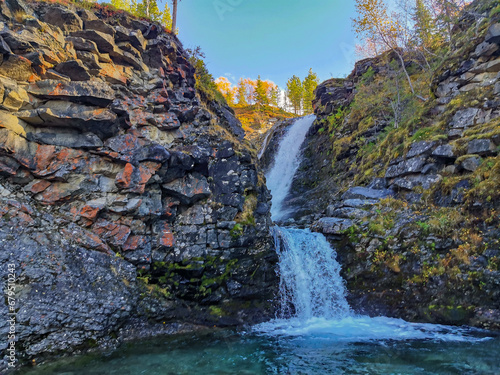 A beautiful waterfall in the autumn mountains beyond the Arctic Circle in the north, in Khibiny, Murmansk region. Panoramic view of a beautiful waterfall in the mountains in autumn, Kola Peninsula