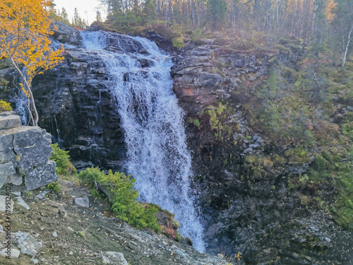 A beautiful waterfall in the autumn mountains beyond the Arctic Circle in the north, in Khibiny, Murmansk region. Panoramic view of a beautiful waterfall in the mountains in autumn, Kola Peninsula photo