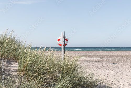 Life preserver on sandy beach on the shore of the North Sea in Denmark photo