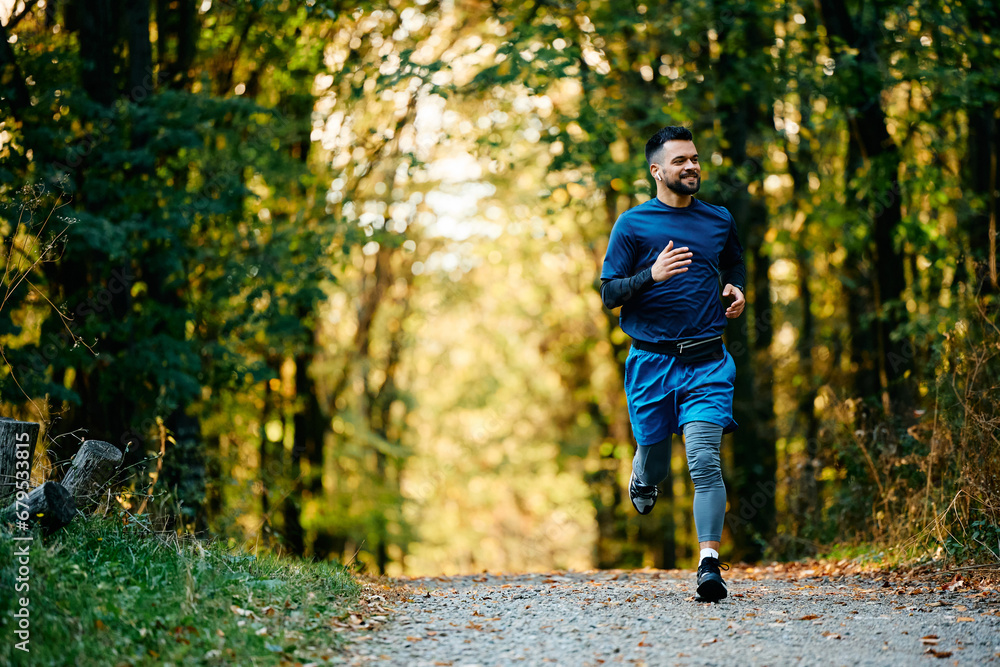 Full length of sportsman running through park. Full length of sportsman running through park.