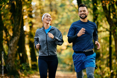 Fototapeta Naklejka Na Ścianę i Meble -  Happy athletic man and his girlfriend jogging in autumn park.