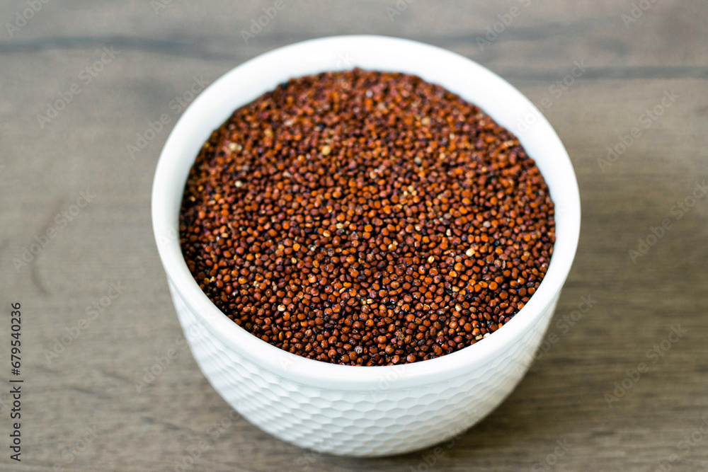 Red quinoa on the white plate on the wooden background. Healthy food and nutrition concept. Safe, ecological, and healthy products Red quinoa on the white plate on the wooden background. Healthy food and nutrition concept. Safe, ecological, and healthy products