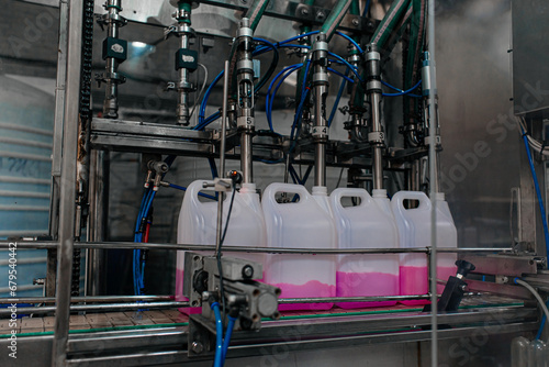 Automatic filling machine pours into plastic PET bottles at modern beverage plant.