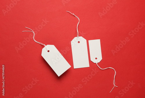 Blank white tags with ropes on red background. Mock up, Template for design. Copy space. Sale, shopping concept