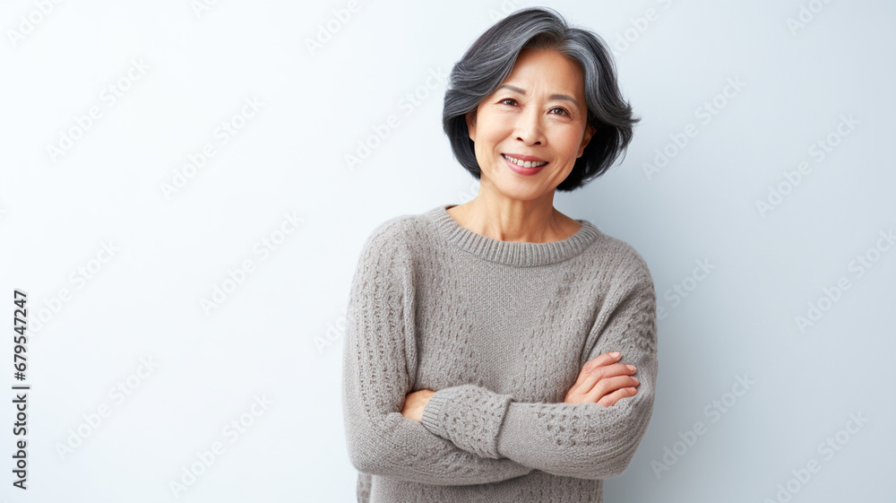 Smiling beautiful 50 year asian old woman in sweater posing in front of a white background.
Smiling beautiful 50 year asian old woman in sweater posing in front of a white background.