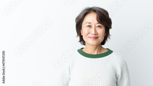 Medium shot portrait of a asian woman in her 50s wearing a cozy sweater against a white background.



