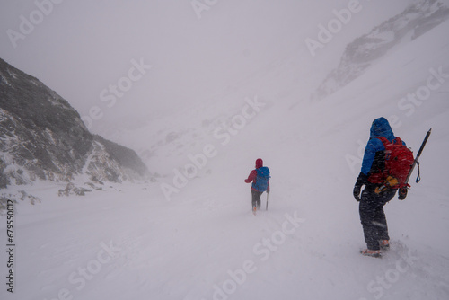 Obraz na płótnie Men with backpack hiking on mountain in snow. Fight for survival in winter mountains. Hiker standing on top of a mountain. Dramatic scenery. Carpathian, Tatras , Europe. Beauty world. w salonie