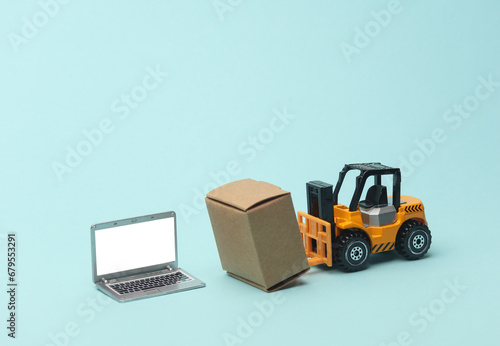 Miniature toy forklift and laptop with boxes on blue background. Logistics, transportation, delivery