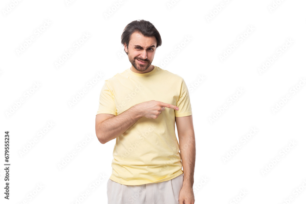 Fototapeta premium young well-groomed european brunette guy with a beard and mustache points his hand to the side