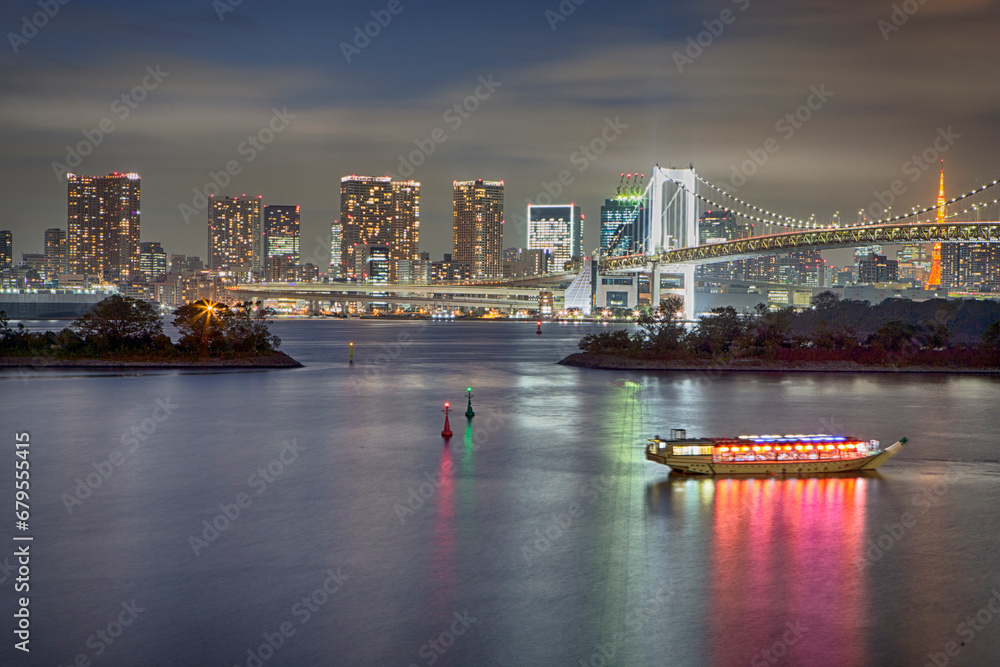 Japan Travel Destinations. Closeup View of Rainbow Bridge in Odaiba Island in Tokyo At Twilight with Tourist Boat and Line of Skyscrapers.