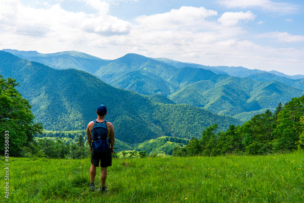 Young man hiking in the beautiful fresh green mountains