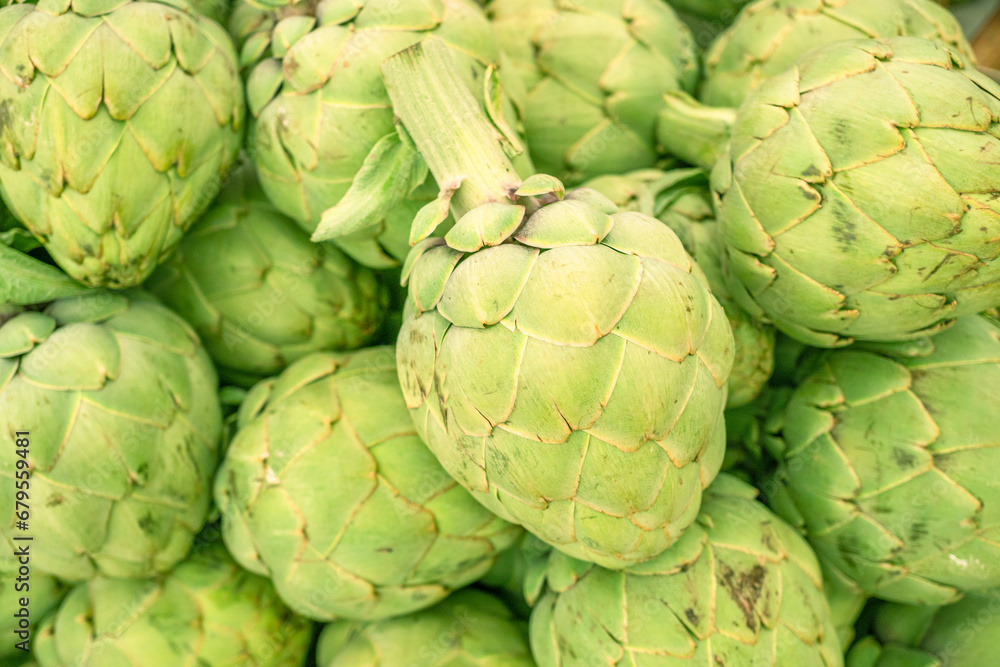 Obraz premium Green french artichoke flowers buds on the farm market stall.