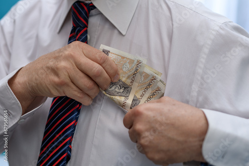Elegancko ubrany mężczyzna wkłada plik banknotów do kieszeni w koszuli 