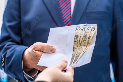 Wręczana koperta z pieniędzmi mężczyźnie ubranemu w elegancki garnitur  photo
