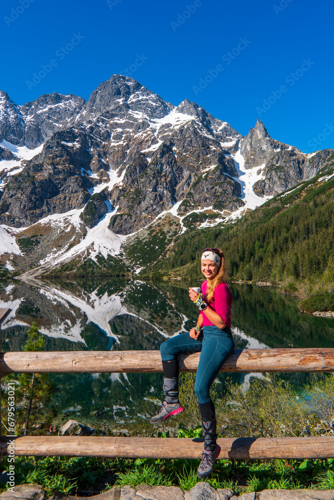 Rear view at happy free woman enjoying beautiful serene morning looking at sea lake and mountains nature landscape scenery starting new day drinking coffee relaxing. Tatras mountain poland